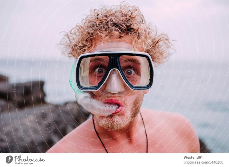 Portrait of young man with diving goggles and snorkel pulling funny faces portrait portraits men males snorkels Adults grown-ups grownups adult people persons