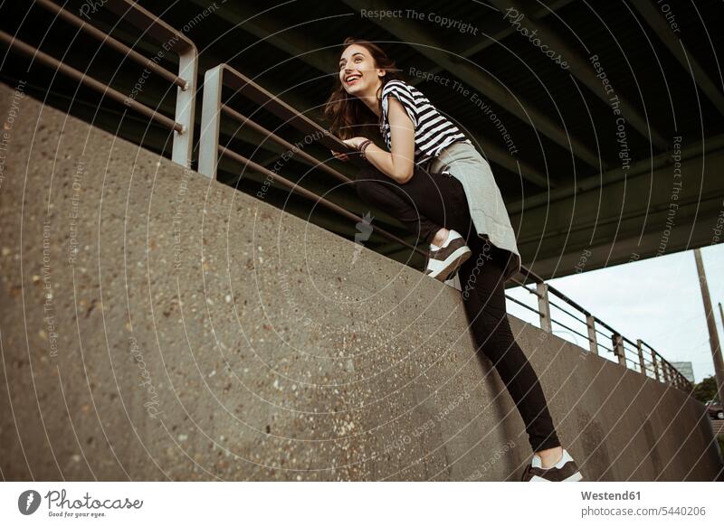 Happy young woman on railing under a bridge laughing Laughter females women positive Emotion Feeling Feelings Sentiments Emotions emotional Adults grown-ups