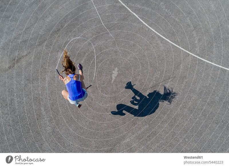 Aerial view of young woman skipping rope, shadow sportive sporting sporty athletic exercising exercise training practising athlete sportswoman athletes