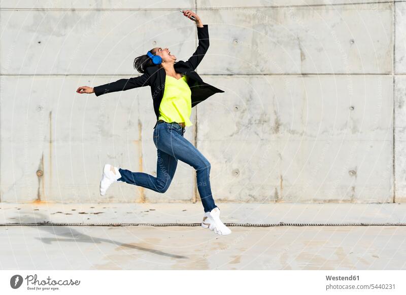 Woman with blue headphones listening music, jumping in the air and taking a selfie Spain wireless Wireless Connection Wireless Technology Wireless Communication