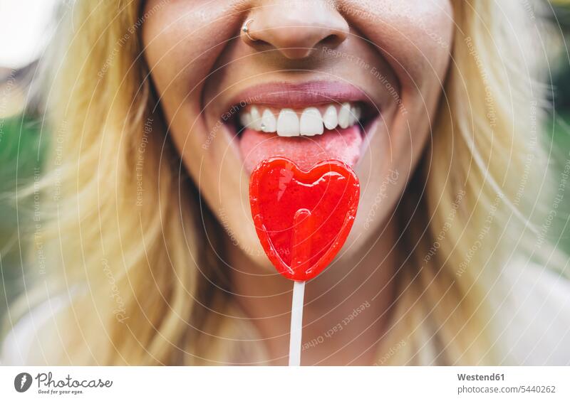 Close-up of young woman licking heart-shaped lollipop Lollipop Lollipops Lolly females women Sweets Candies Sweet Food foods food and drink Nutrition