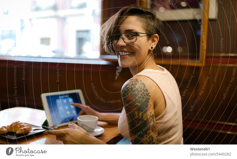 Portrait of tattooed young woman sitting in a coffee shop using digital tablet Gijon top tops wireless Wireless Communication Wireless Connection