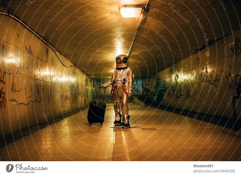 Spaceman in the city at night in underpass with rolling suitcase astronaut astronauts spaceman spacemen Trolley Bag town cities towns by night nite