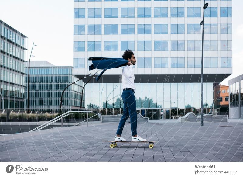 Spain, Barcelona, young businessman riding skateboard in the city men males town cities towns Businessman Business man Businessmen Business men Skate Board