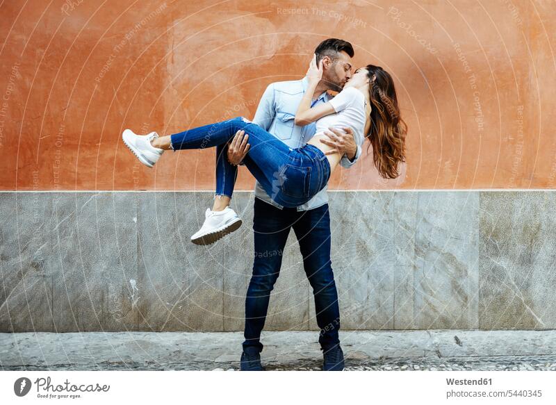 Carefree couple in love kissing in front of a wall outdoors Love loving carefree walls kisses twosomes partnership couples positive Emotion Feeling Feelings