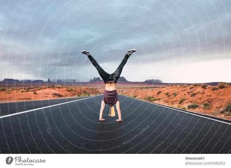USA, Utah, Young man dong handstand on road to Monument Valley upside down young man young men streets roads standing handstands United States
