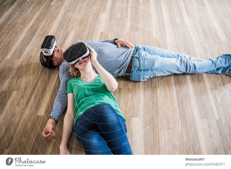 Young couple lying on floor in empty apartment wearing VR glasses twosomes partnership couples Virtual Reality Glasses Virtual-Reality Glasses