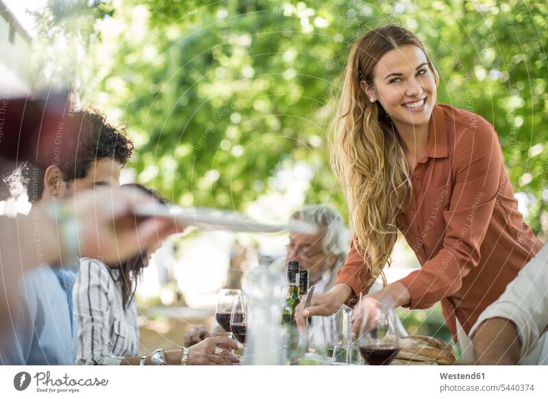 Smiling woman dishing up at family lunch in garden group of people Group groups of people friends smiling smile Red Wine Red Wines celebrating celebrate