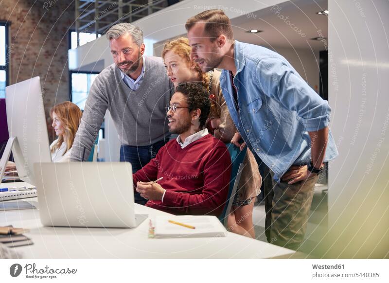 Colleagues looking over shoulder of young man working in modern office team watching offices office room office rooms Female Colleague smiling smile At Work PC