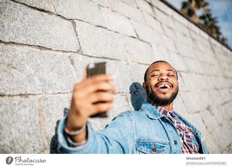 Portrait of laughing young man taking selfie with cell phone Selfie Selfies men males Adults grown-ups grownups adult people persons human being humans