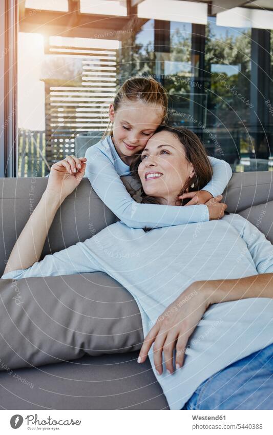 Daughter embracing mother sitting on terrace daughter daughters embrace Embracement hug hugging terraces couch settee sofa sofas couches settees mommy mothers