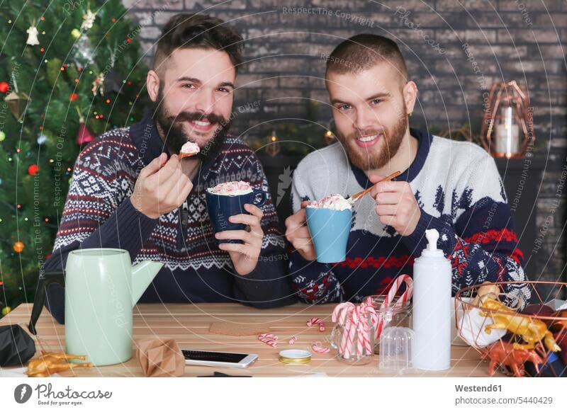 Happy gay couple drinking hot chocolate with cream and chopped candy canes at Christmas time portrait portraits Gay Couple Gays same-sex couple woman and woman