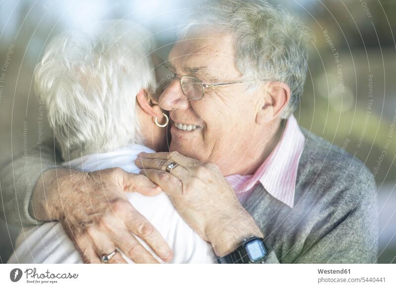 Happy senior couple hugging behind windowpane window glass window glasses windowpanes Window Pane happiness happy windows smiling smile embracing embrace