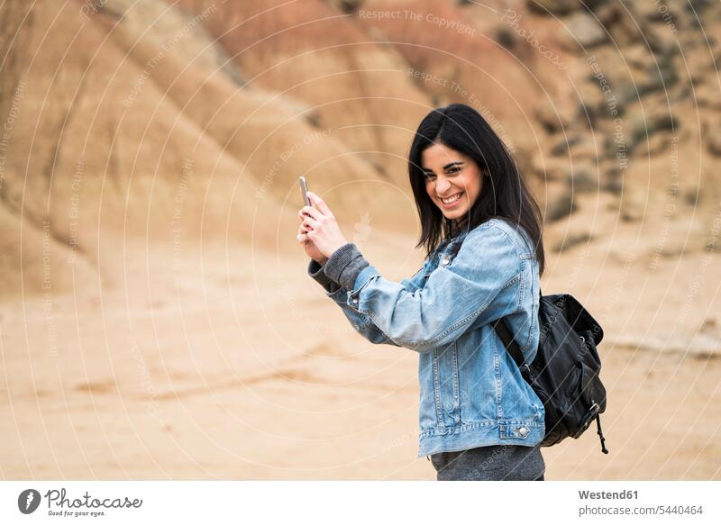 Spain, Navarra, Bardenas Reales, laughing young woman in nature park taking selfie with cell phone females women Laughter Smartphone iPhone Smartphones Adults