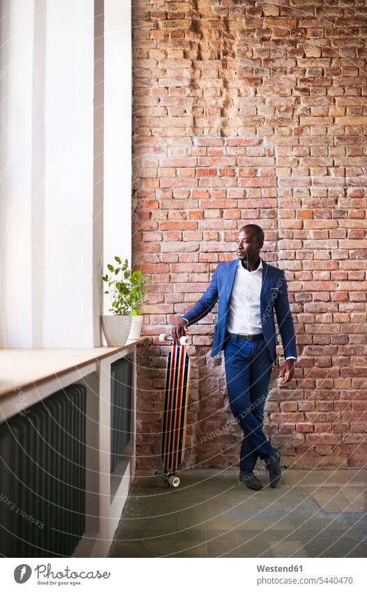 Businessman with longboard at brick wall by the window Business man Businessmen Business men skateboard Skate Board skateboards business people businesspeople