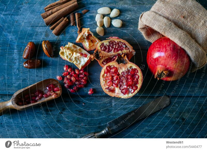 Sliced and whole pomegranate, pomegranate seed, dates, almonds and cinnamon sticks on wood nobody Freshness fresh Arrangement Positioning Positionings