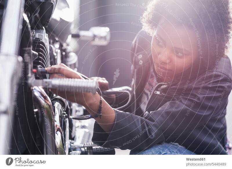 Young woman maintaining her motorcycle females women motorbike Motor Cycle Adults grown-ups grownups adult people persons human being humans human beings
