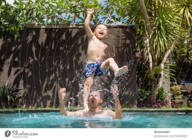 Father and son having fun in swimming pool father pa fathers daddy dads papa sons manchild manchildren Fun funny pools swimming pools parents family families