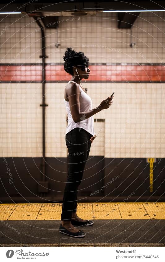 USA, New York City, Manhattan, woman waiting at subway station platform females women underground station platform Subway Platform Adults grown-ups grownups