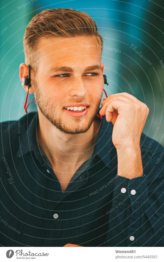 Young man wearing headset outdoors men males earphones ear phone ear phones headphones Adults grown-ups grownups adult people persons human being humans