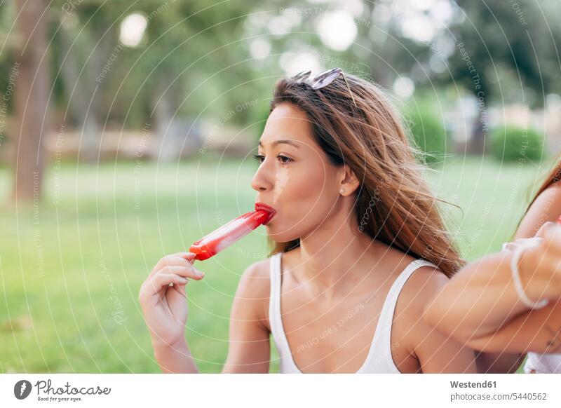 Woman having a popsicle in park holding parks Sweet Food sweet foods food and drink Nutrition Alimentation Food and Drinks nature natural world Picnic