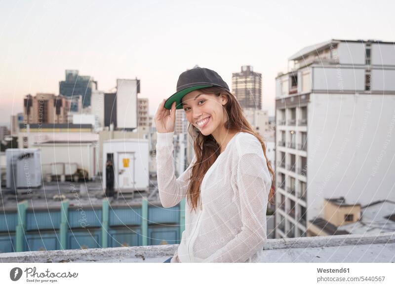 Young woman standing on a rooftop terrace, smiling females women happiness happy roof terrace deck carefree smile Adults grown-ups grownups adult people persons