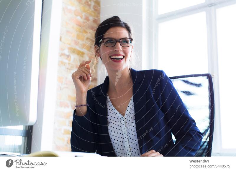 Laughing businesswoman at desk in office businesswomen business woman business women laughing Laughter desks offices office room office rooms business people