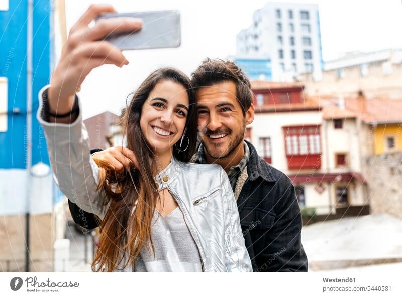 Smiling couple taking a selfie in the city twosomes partnership couples Selfie Selfies mobile phone mobiles mobile phones Cellphone cell phone cell phones