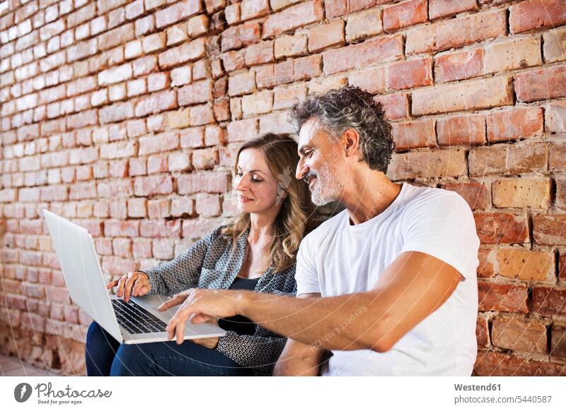 Businessman and woman sitting in a loft, using laptop, founding a start-up company Seated company foundation setting up business startup young business start up