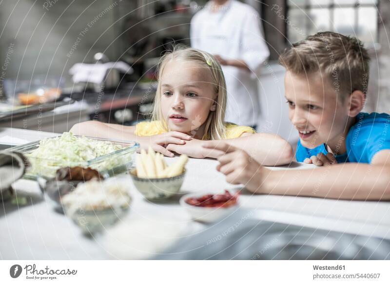 Inquisitive boy and girl in kitchen cooking class boys males females girls child children kid kids people persons human being humans human beings ingredient