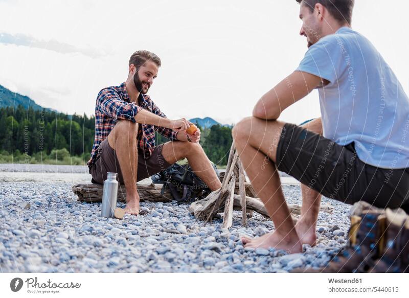 Germany, Bavaria, two hikers having a rest at camp fire on gravel bank friends friendship sitting Seated barefoot naked feet naked foot Barefeet Bare Feet