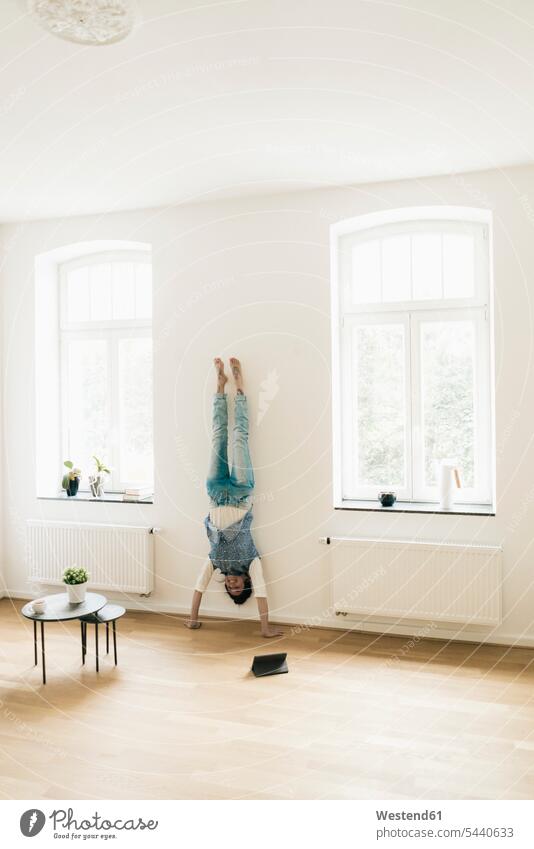 Woman at home doing a handstand at the wall woman females women handstands Adults grown-ups grownups adult people persons human being humans human beings