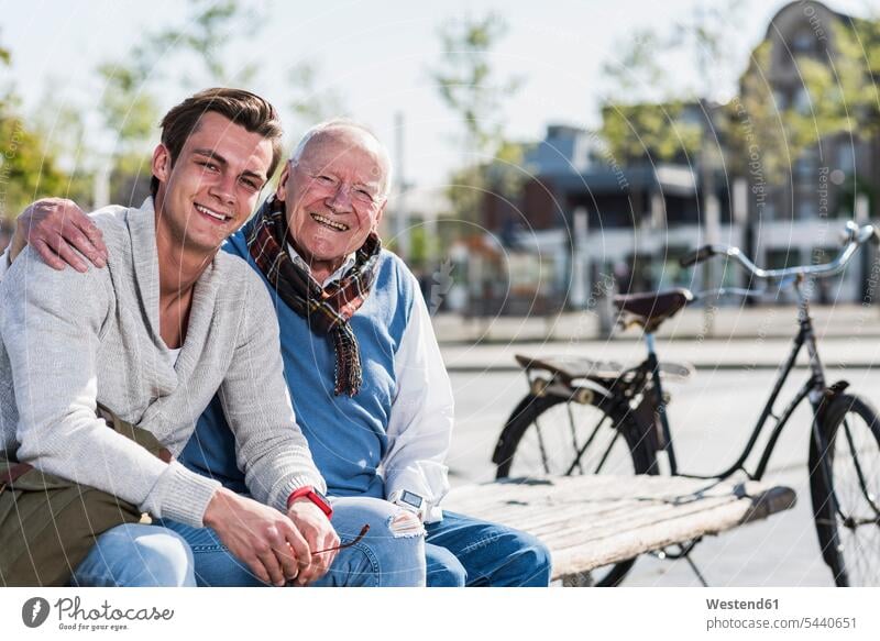 Portrait of happy senior man with adult grandson sitting on a bench happiness Seated smiling smile grandsons benches grandfather grandpas granddads grandfathers
