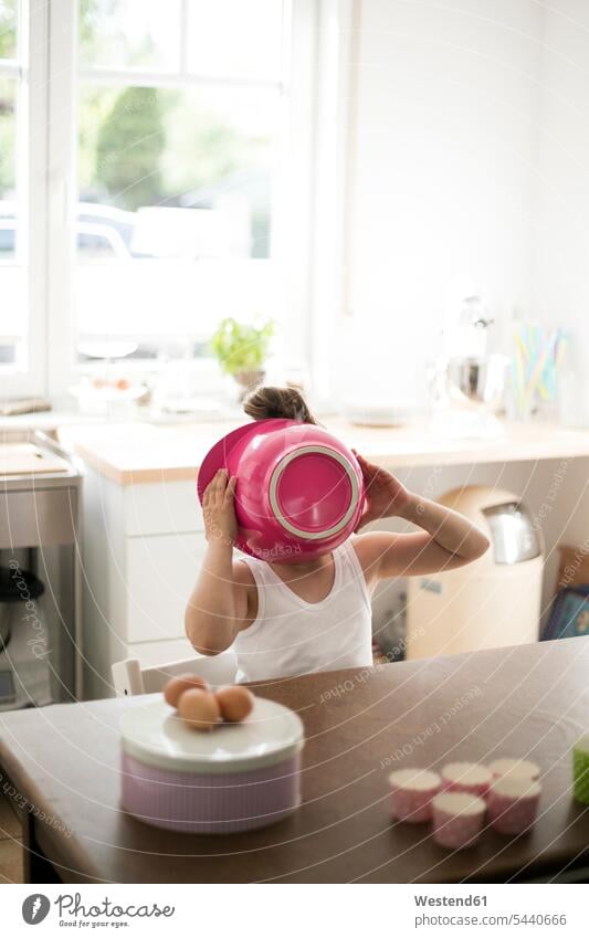 Little girl in kitchen covering her face with pink mixing bowl Bowl Bowls females girls hiding hide baking bake child children kid kids people persons