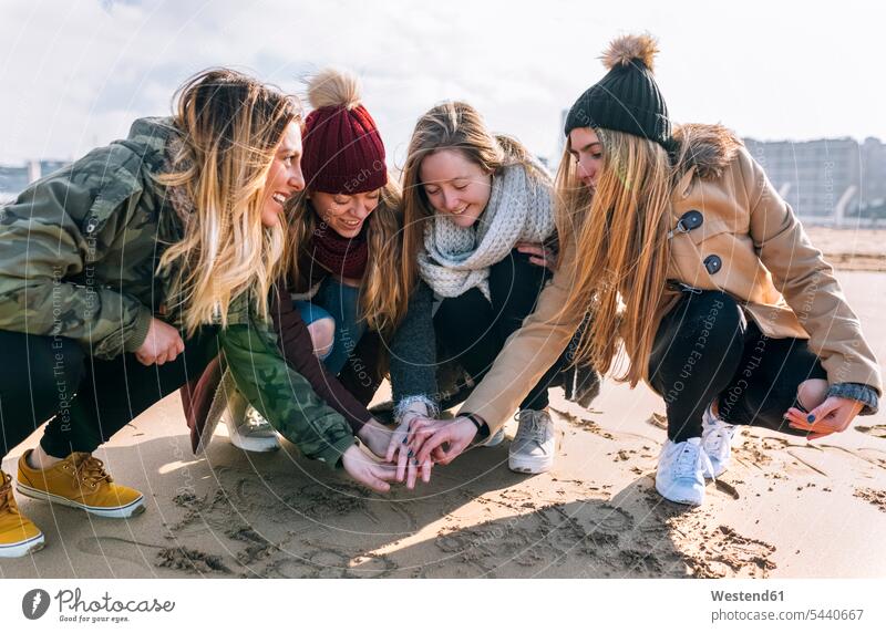 Four friends joining hands on the beach mate female friend beaches human human being human beings humans person persons human hand human hands connect cower