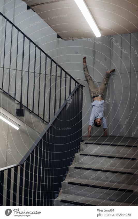 Young man doing a handstand in staircase handstands staircases stairwell men males stairs stairway Adults grown-ups grownups adult people persons human being