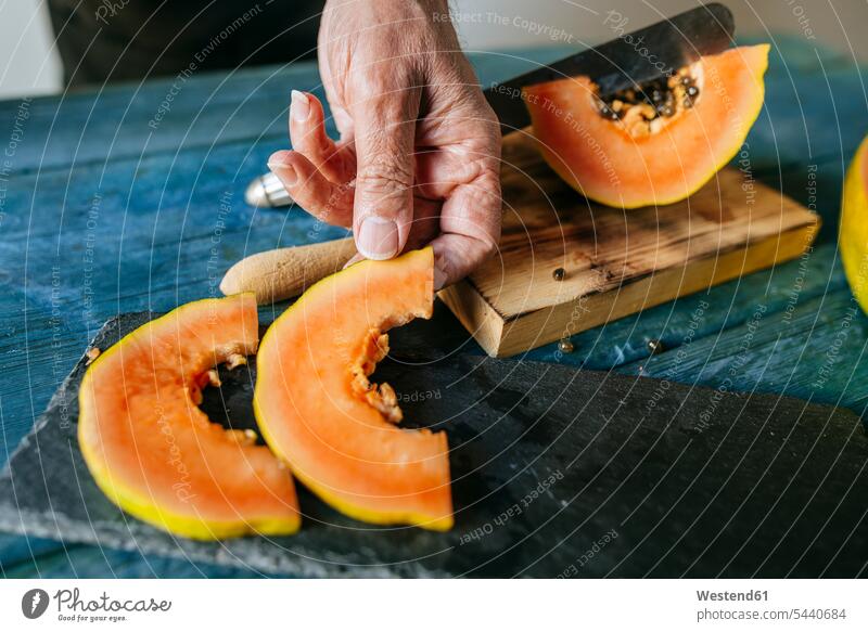 Close-up of man's hands placing pieces of papaya on slate plate cutting Freshness fresh half halves halved men males preparation prepare preparing knife knives