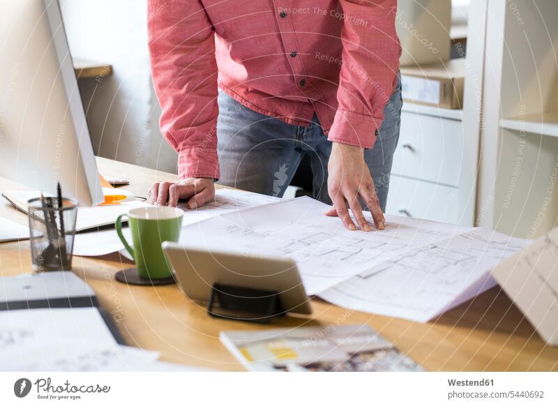 Close-up of man working on blueprint at desk in office offices office room office rooms workplace work place place of work construction plan building plan