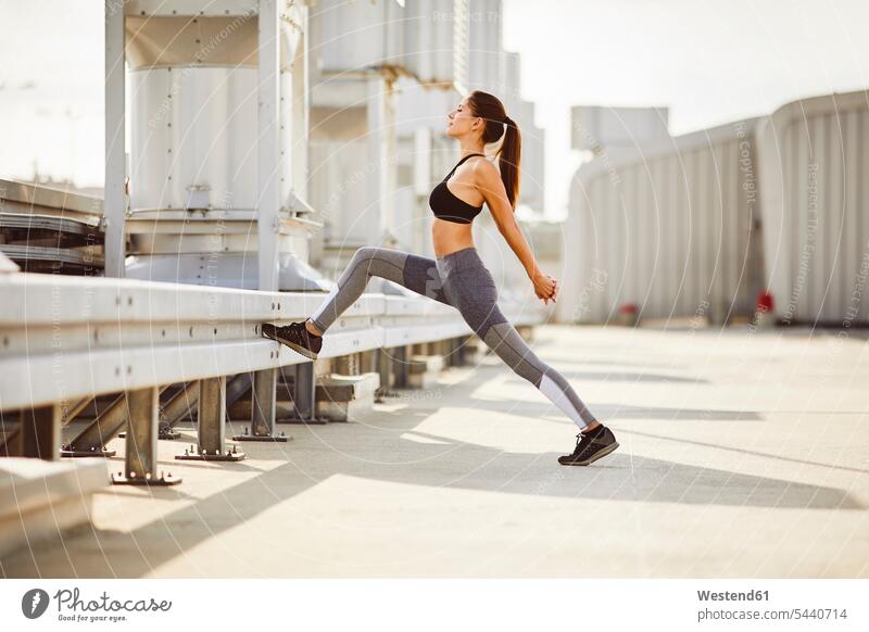 Young woman stretching during city workout exercising exercise training practising females women Adults grown-ups grownups adult people persons human being