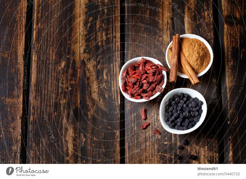 Bowl of cinnamon powder with cinnamon sticks, goji berries and chokeberries on wood food and drink Nutrition Alimentation Food and Drinks Goji Chinese boxthorn
