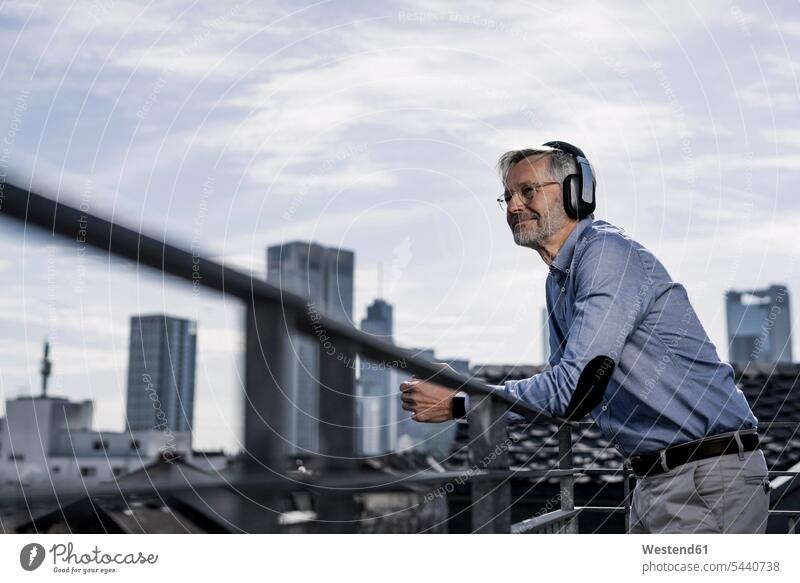 Grey-haired man with headphones enjoying city view break Businessman Business man Businessmen Business men hearing music headset relaxed relaxation