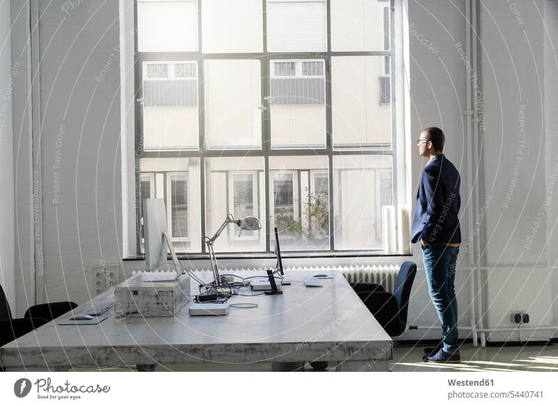 Young businessman looking out of office window view seeing viewing Businessman Business man Businessmen Business men windows agency agencies offices office room