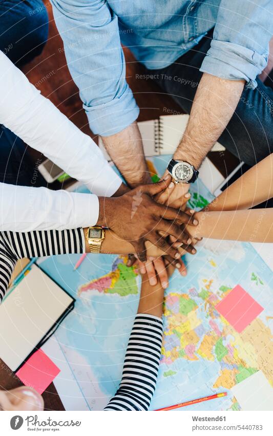 Group of friends stacking hands above world map human hand human hands travelling traveling maps people persons human being humans human beings friendship