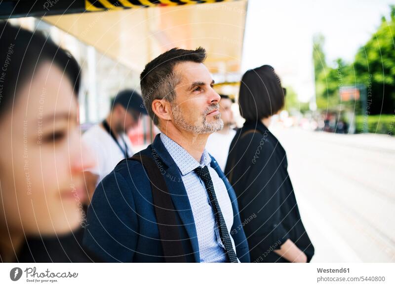 Businessman waiting at the bus stop busstops commuter commuters station transportation Business man Businessmen Business men business people businesspeople