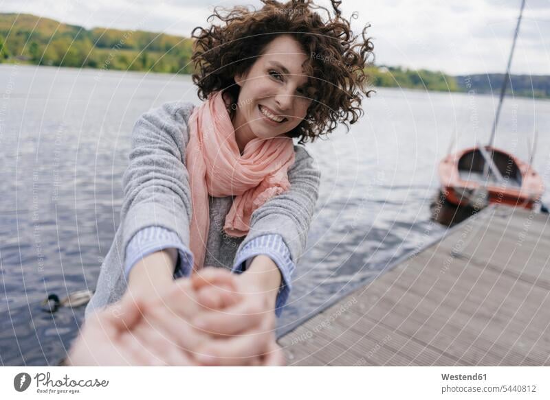 Woman standing on jetty, pulling on man's hand leisure free time leisure time human hand hands human hands jetties boat boats woman females women lake lakes