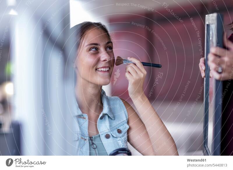 Girl applying make up while mother holding mirror mirrors Makeup Make-up Paint Beauty smiling smile girl females girls applying makeup painting face child