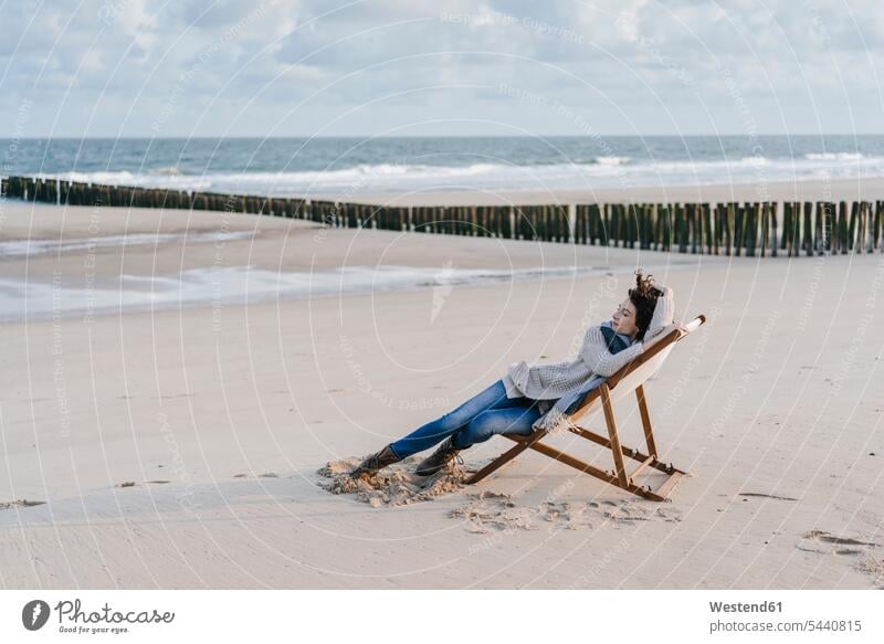 Woman sitting on deckchair on the beach Seated beaches woman females women Adults grown-ups grownups adult people persons human being humans human beings