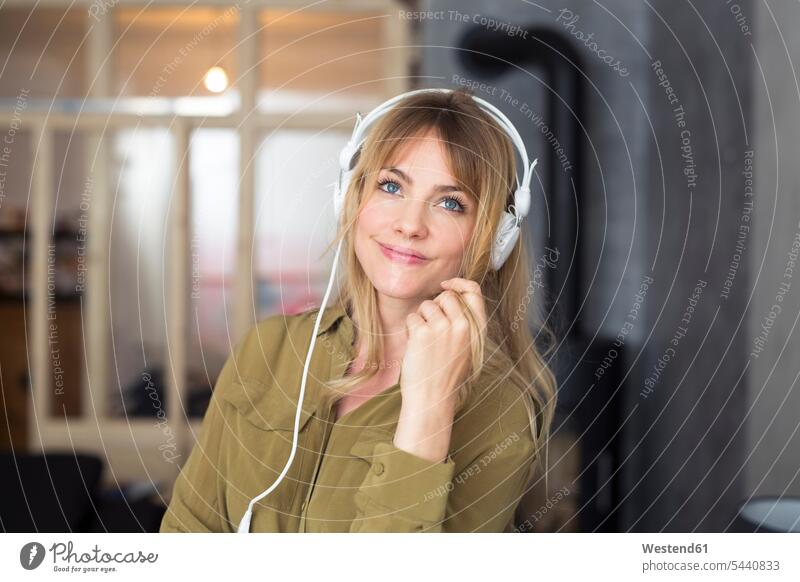 Smiling blond woman listening to music with headphones hearing headset portrait portraits smiling smile females women blond hair blonde hair Adults grown-ups