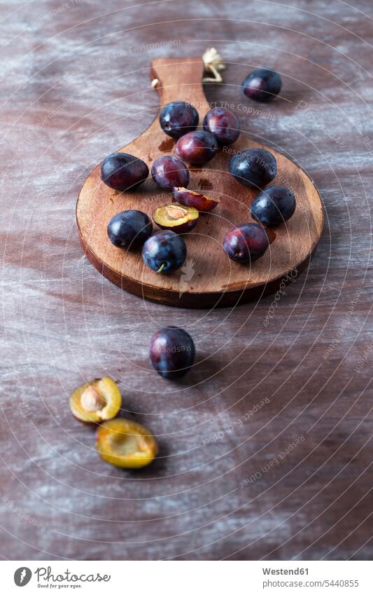 Sliced and whole plums on wooden board food and drink Nutrition Alimentation Food and Drinks sliced half halves halved juicy copy space wooden boards