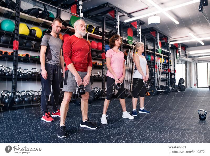 Group of fit seniors with personal trainer in gym exercising exercise training practising weight weights gyms Health Club senior adults old lifting